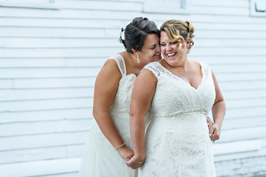 A bride whispering into her new brides ear and making her laugh.